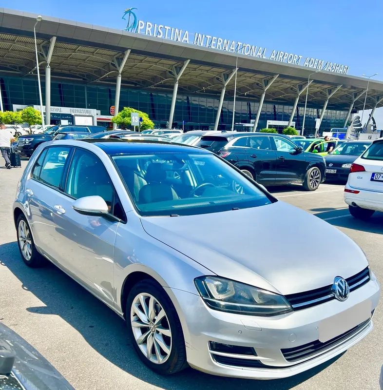Silver Volkswagen Golf parked in front of the Prishtina International Airport terminal